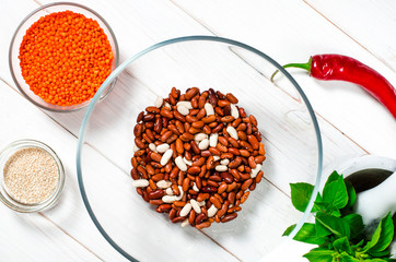 The bean diet. Beans, lentils, sesame garlic and basil in glass plates stand on a wooden table