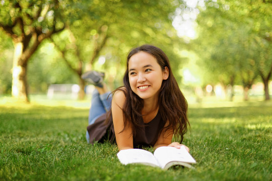 Kazakh beautiful girl reading a book in the summer park