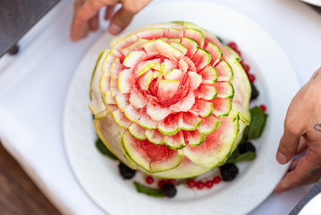 Watermelon sliced in the form of a flower in the hands of a waiter