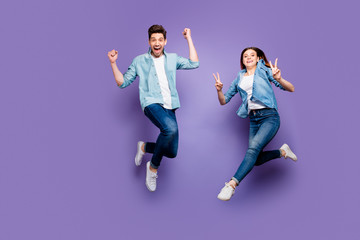 Fototapeta na wymiar Full size photo of crazy cheerful brown hair redhair funny funky spouses jump have rest raise fists scream yeah make v-signs wear denim jeans modern outfit isolated violet purple color background
