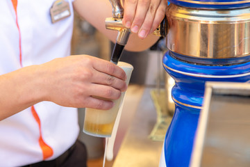The bartender pours beer into a glass