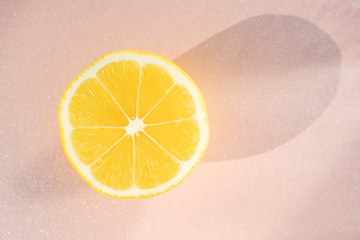 Half sliced ​​fresh lemon on a pastel pearl light pink background. Concept of healthy...