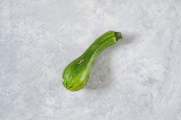 One spoiled zucchini on a gray background. Ugly food concept, organic vegetables. Top view, flat...