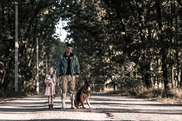 man holding hands with child near german shepherd dog, post apocalyptic concept