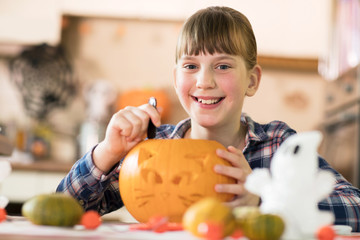 Fototapeta premium Portrait Of Girl Carving Halloween Lantern From Pumpkin At Home