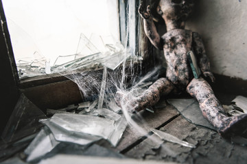 selective focus of cobweb near scary and burnt baby doll, post apocalyptic concept