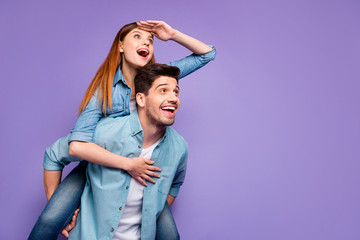 Portrait of excited funny funky two people look at sky space hold hand near eyes hug piggyback wear...
