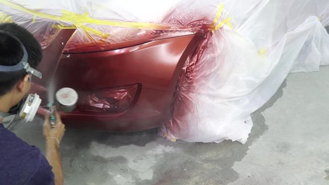 Quick car paint repair ,It takes one to two hours.spray gun with paint for painting a car ,Man with protective clothes and mask painting car using spray compressor