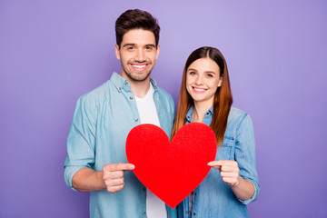 Portrait of romantic two married people couple hold paper card red heart gift for valentine day enjoy date wear stylish trendy outfit isolated over purple violet color background
