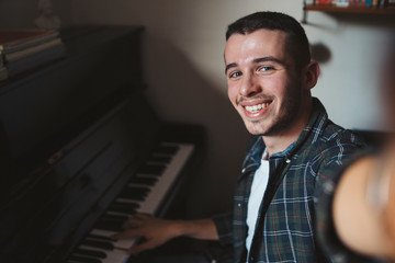 Young man takes a selfie while playing the piano - Millennial in a moment of relaxation at home