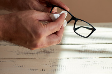 man hands cleaning eye glasses, on white table background