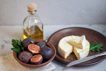 Ripe, beautiful, purple figs. Sweet and juicy. Mediterranean fruit is very healthy. On a plate is Brie cheese. On a light gray background copyspace there is an empty place. Food for vegetarians. 