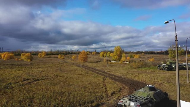 Armoured personnel carrier goes on the field. APC. Aerial video. Drone video. Autumn yellow trees and blue sky. Military trainings
