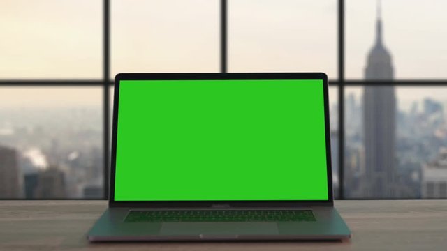 Zoom-in view mock-up notebook with modern green open display on wooden desk in office of New York company. Background cityscape of Big Apple.