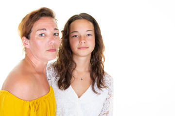 middle aged curly woman posing with little daughter teenager on white wall background