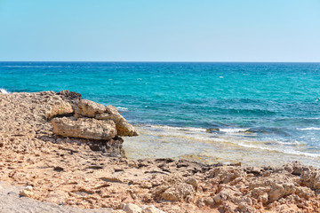 Shot of a beach with stones and transparent water of the azure mediterranean sea, surrounded by a picturesque nature of Cyprus. Ayia Napa.