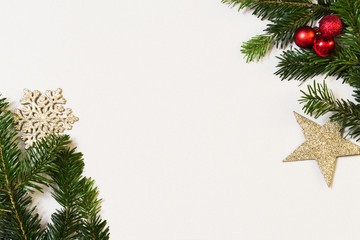 Christmas frame with copy space, green fir branches, golden stars and red balls on white background, top view