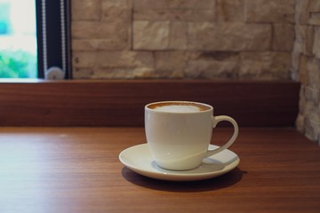 Close up of white coffee cup on wood table in coffee cafe.	