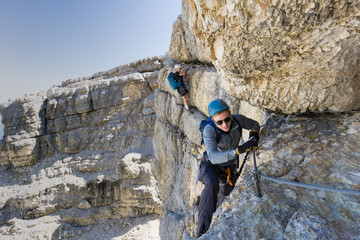 two mountain climbers on an exposed Via Ferrata in the Dolomites of Italy