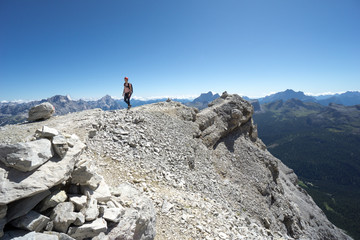 woman climber hiking along a rocky summit ridge in the Dolomites of Italy
