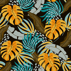 Summer seamless tropical pattern with beautiful yellow and blue leaves and plants on dark background.  Beautiful exotic plants.   Jungle leaf seamless vector floral pattern background.