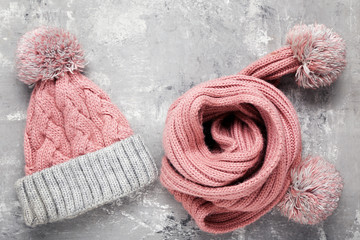 Knitted hat and scarf on grey background