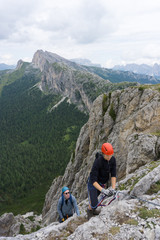 man and woman in their twenties climb a steep Via Ferrata for fun during their holidays