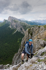 man in his twenties climbing a steep Via Ferrata in the Dolomites of Alta Badia