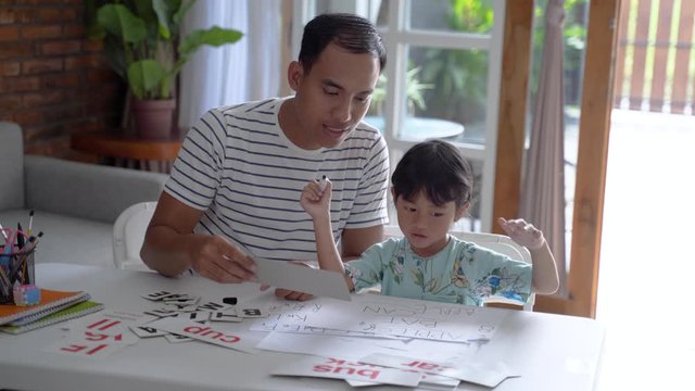 happy asian father teaching letter to her daughter at home. read and write lesson