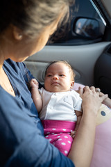 portrait of infant baby laying on mother's lap while in the car