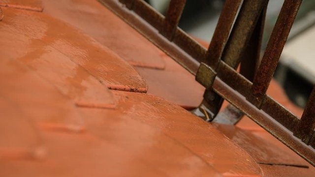  Water on the tiles of a roof is flowing down under a snow guard into the rain gutter on a rainy autumn day in Germany