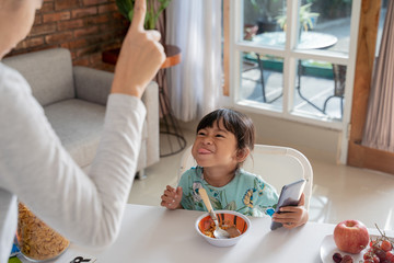 portrait of a mother get angry with stubborn kid using mobile phone