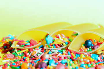 Fototapeta na wymiar Abstract food background. Durum wheat pasta and colorful candies over yellow background. Incompatible products concept.
