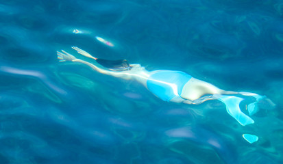 A man swims in the blue water of the sea