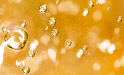 Bubbles of air on the smooth surface of golden water as an abstract background