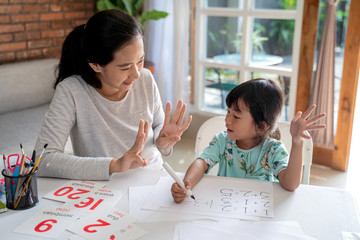 mother teaching basic math to her little daughter at home