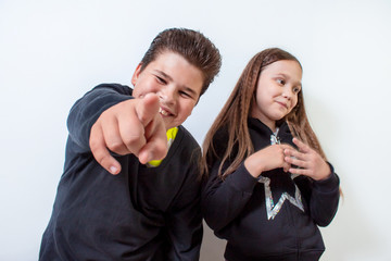 A little girl and a boy point at the camera