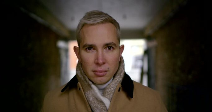 attractive blond guy is looking at camera, standing in lane in downtown in fall day