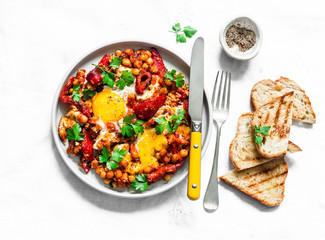Shakshuka with baked sweet peppers and chickpeas on a light background, top view