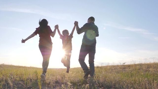 happy family father a son and mom run go slow motion funny video concept. happy teamwork dad man mom girl and son boy child running hold hands run go on the field in lifestyle nature . happy family