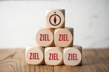 many cubes with the German word for goal and a compass symbol on wooden background