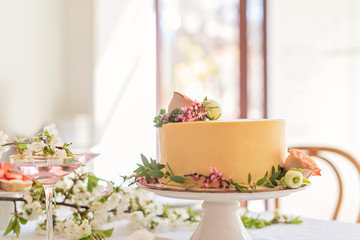 Wedding cake with flowers without piece on boho style table setting.