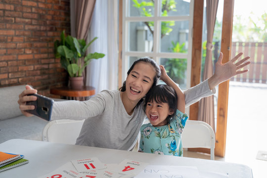 Happy Asian Mother And Kid Taking Selfie Together At Home