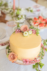 Festive bridal cake with flowers, boho style table setting. Holiday cake on table