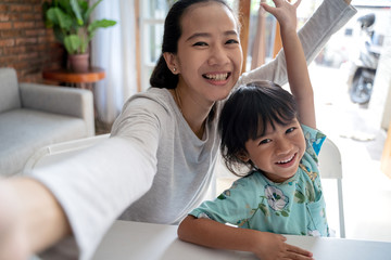 happy asian mother and kid taking selfie together at home