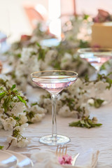 Fruits martini in a festive martini glass on wedding boho`s table with flowers on the background. Holiday table setting
