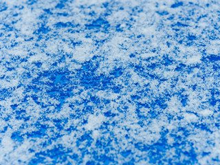 Fototapeta na wymiar Abstract background. Melted and crystallized snow on a blue surface. Close-up