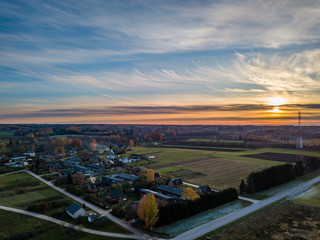 Aerial view of colorful sunset over countryside village with telecommunication tower in a distance