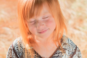 Portrait of a beautiful red-haired girl with freckles and closed eyes