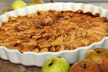 Autumn homemade apple pie - charlotte. on white ceramic plate on wooden background with fresh apples